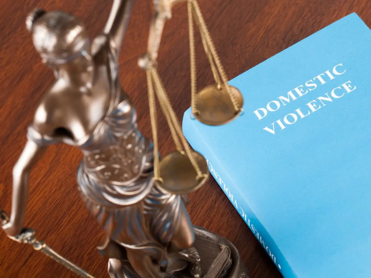Lady Justice statue beside a domestic violence law book