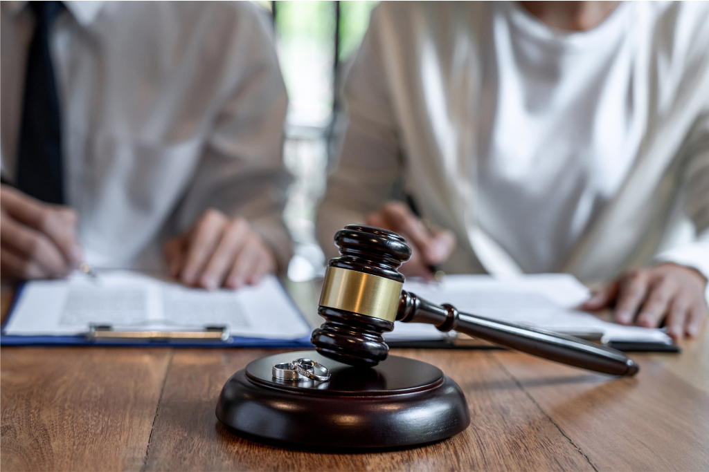 A gavel and two people signing divorce papers, symbolizing the process and legal aspects of gray divorce.